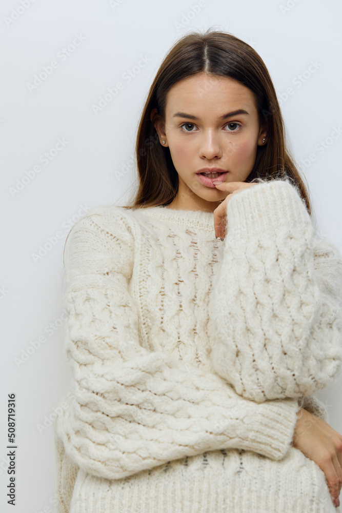 a beautiful, pleasant young woman stands on a light background in a stylish, warm autumn white sweater and poses with her arms crossed on her chest in a relaxed pose, looking sweetly at the camera a beautiful, pleasant young woman stands on a light background in a stylish, warm autumn white sweater and poses with her arms crossed on her chest in a relaxed pose, looking sweetly at the camera