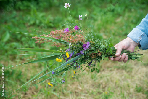 closeup of wild flowers bouquet in hand of woman in a meadow