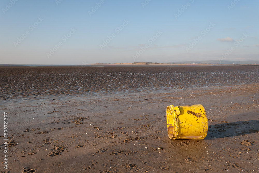A yellow plastic bucket litters the beach at Instow, Devon A yellow plastic bucket litters the beach at Instow, Devon