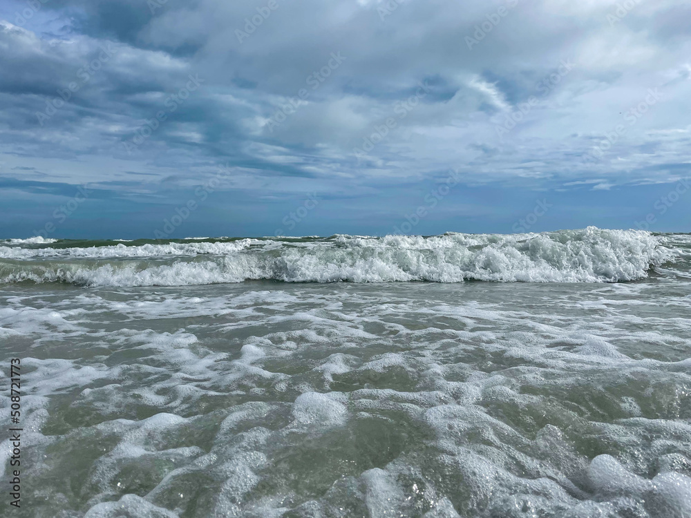 Fototapeta premium Meer mit Wellen aus der Sicht von der Küste mit bewölktem Himmel