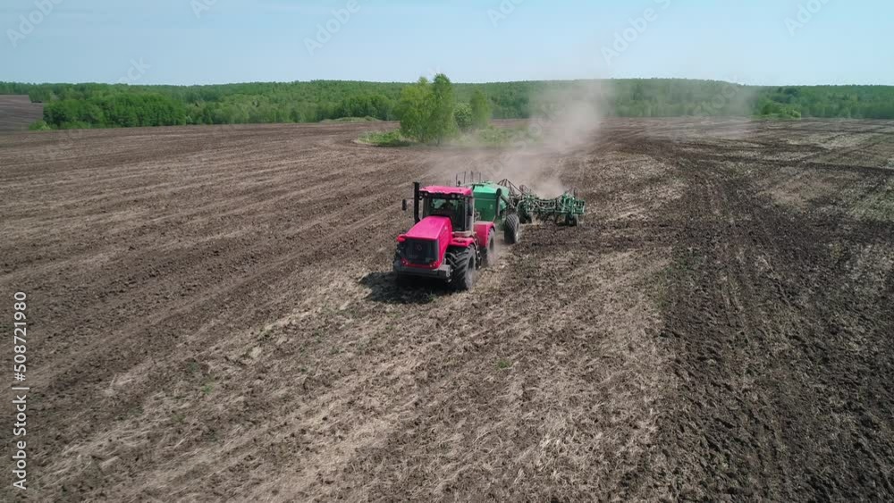 Aerial view of an agricultural tractor performing plowing tillage for sowing crops. A cultivator working in the field with dry dusty soil Aerial view of an agricultural tractor performing plowing tillage for sowing crops. A cultivator working in the field with dry dusty soil