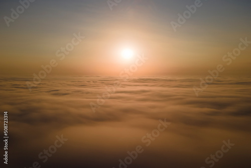 Aerial view from airplane window at high altitude of dense puffy cumulus clouds flying in evening © bilanol