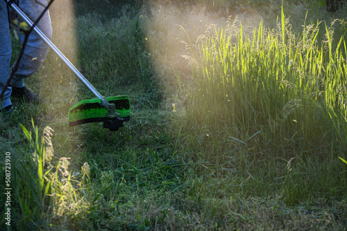 The guy mows, cuts, cuts grass in an overgrown garden, garden trimmer or moto-scythe.
Gardening, garden cleaning. We do not care...