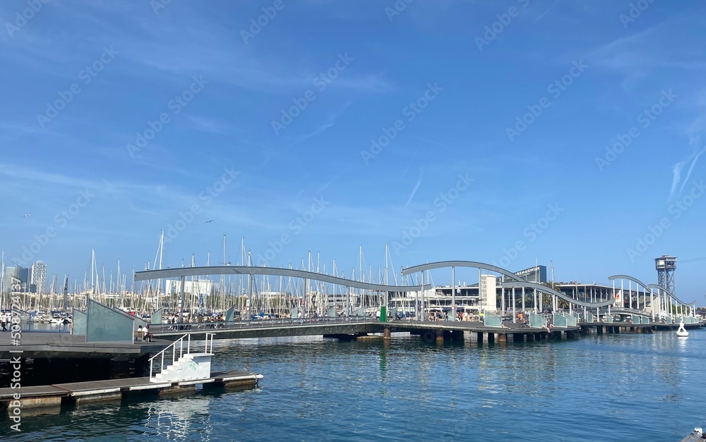 Boats in the port of Barcelona. Bridge over the Mediterranean Sea. Beautiful reflections in the water of the boats. Tourist places to visit in Barcelona, Spain. Port vell. Barcelona’s port background.
