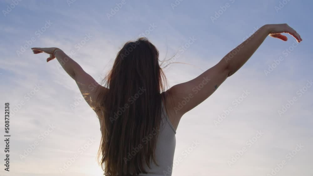Medium shot low angle, young white skin woman meditating and breathing, raising her arms to the sky