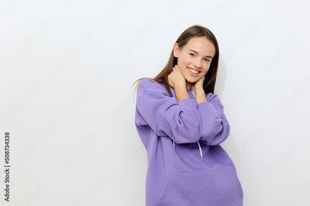 a beautiful woman stands on a white background in a purple tracksuit joyfully presses her hands to her neck, slightly hunched over a beautiful woman stands on a white background in a purple tracksuit joyfully presses her hands to her neck, slightly hunched over