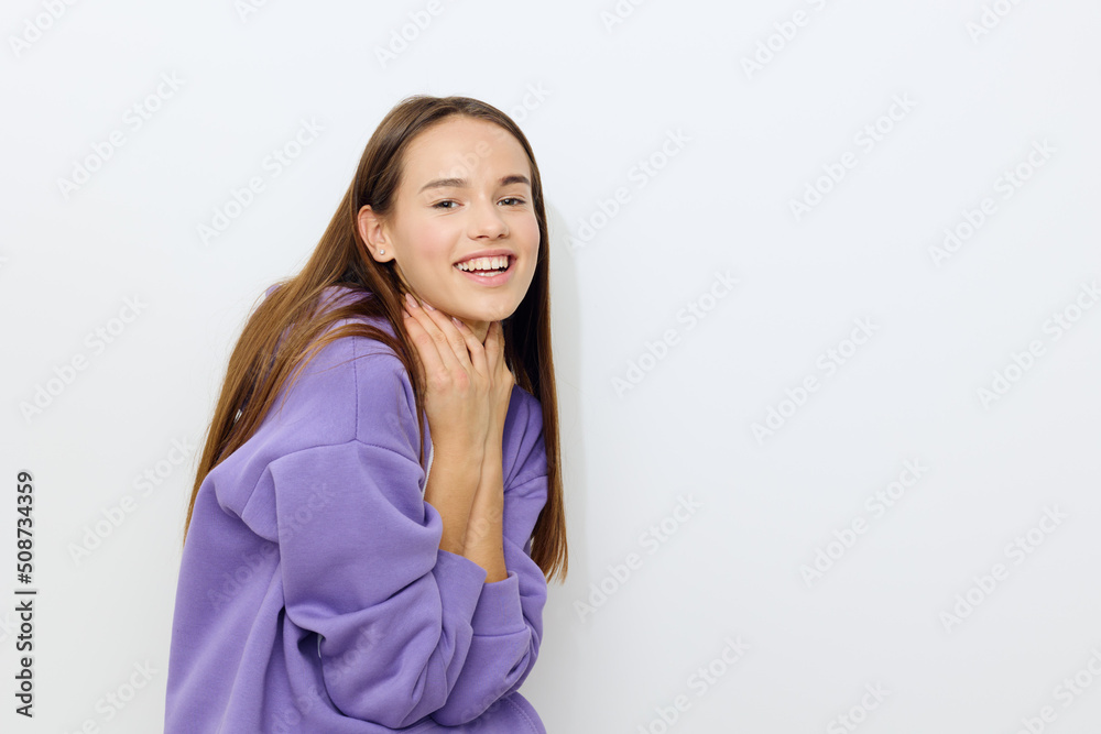 a beautiful woman stands on a white background in a purple tracksuit joyfully presses her hands to her neck, slightly hunched over a beautiful woman stands on a white background in a purple tracksuit joyfully presses her hands to her neck, slightly hunched over