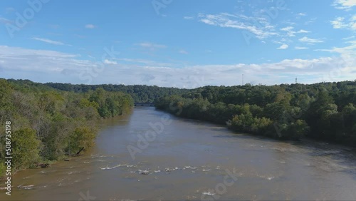 aerial footage of the silky brown waters of the Chattahoochee river surrounded by vast miles of lush green trees with blue sky and clouds at the Cochran Shoals Trail in Marietta Georgia USA photo