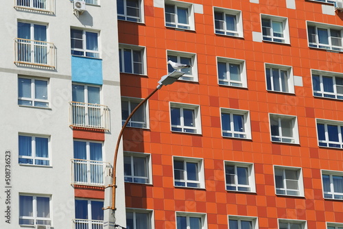 Modern high-rise building in a residential complex. Many windows. A seagull sits on a lamppost.