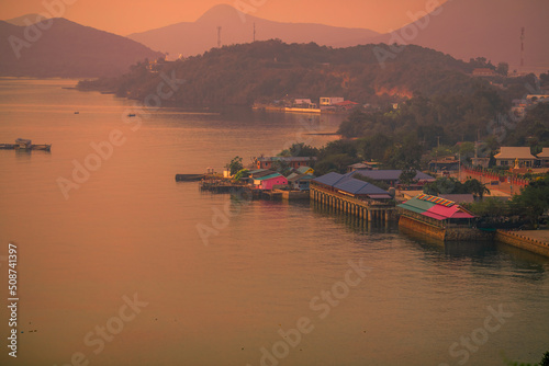 Blurred nature background of the morning sun by the sea, a beautiful golden light, among the trees, rocks and local fishing boats, the beauty of nature during the day.