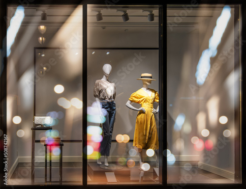 Shop windows and mannequins. Fashion Store exterior. City Night Boutique. Front View from street outdoor. LED light. Selective focus
