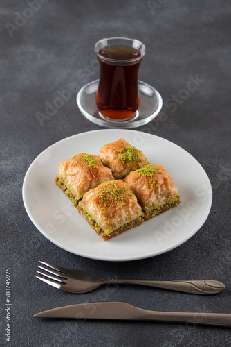Pistachio baklava on a white plate with Turkish tea

