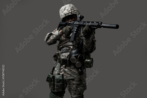 Portrait of brave army man dressed in modern camouflage uniform aiming rifle.