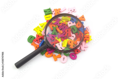 Heap of colorful wooden letters and magnifying glass isolated on white background.