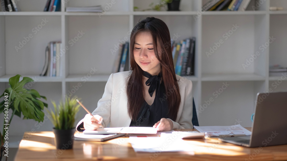 Charming asian businesswoman sitting working on laptop in office. Charming asian businesswoman sitting working on laptop in office.