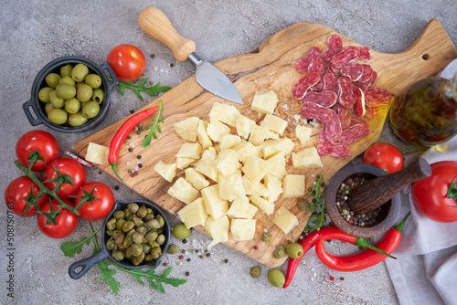 Chopped Parmesan cheese and vegetables on grey table at domestic kitchen photo