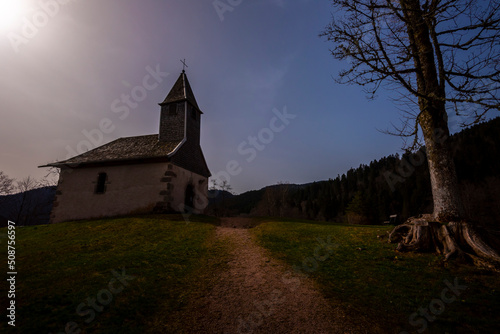 Nuit américaine sur une petite chapelle européenne en haut d'une colline au milieu des montagnes de sapin. photo