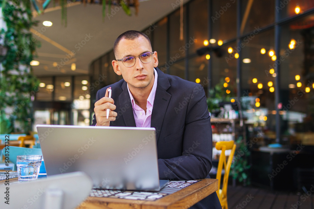 Young handsome businessman working on his laptop while sitting in a cafe Young handsome businessman working on his laptop while sitting in a cafe