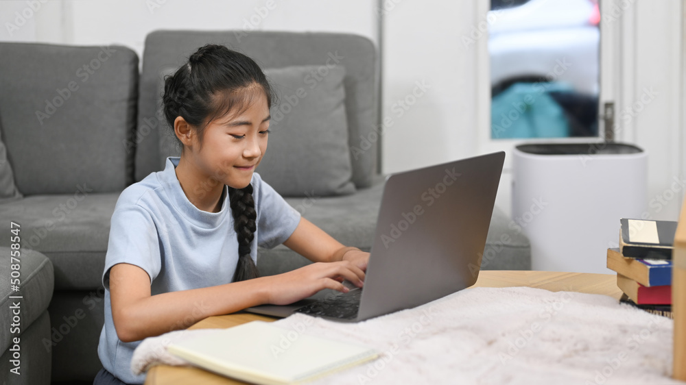 Asian girl having online class, doing homework in living room. Virtual education, homeschooling concept Asian girl having online class, doing homework in living room. Virtual education, homeschooling concept