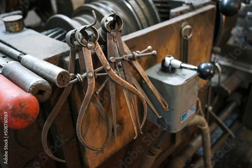 Closeup of a measuring special equipment like calipers, dividers & compass of old Lathe Machinery. Vintage Industrial Machinery in a old factory. Selective focus.