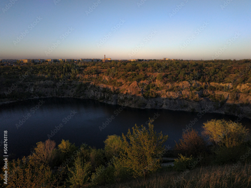 Evening landscape overlooking a flooded quarry in Ukraine. Flooded and abandoned granite quarry