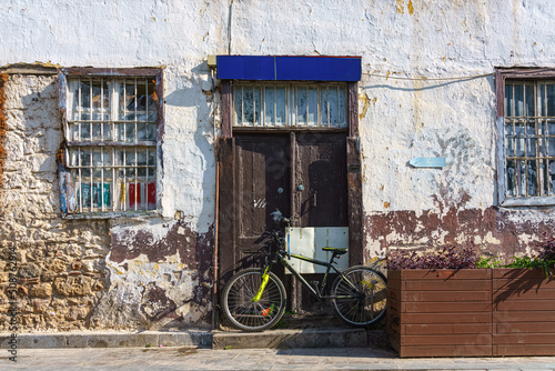 Facade of the old brick house in the old town of Antalya, Turkey. Modern bicycle parked against a wooden door.