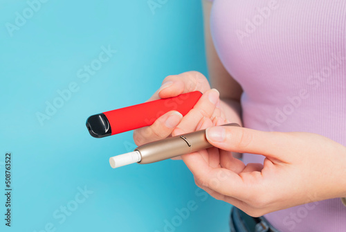 Disposable electronic cigarette and iqos in hand. an alternative way of consuming tobacco. modern smoking  choice