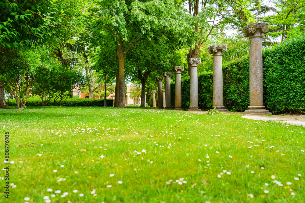 Park of lush vegetation with ancient columns of Roman style