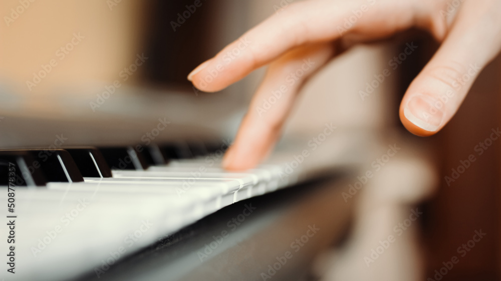 Female hand presses the keys of a synthesizer, selective focus, side view Female hand presses the keys of a synthesizer, selective focus, side view