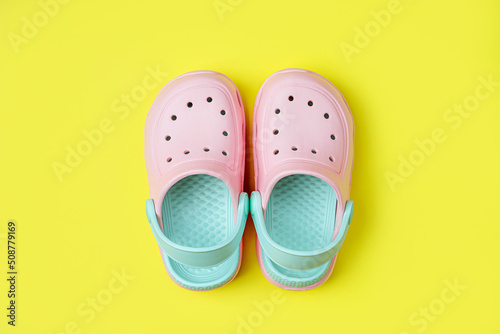 Fototapeta Pink kids clogs beach slippers on yellow background