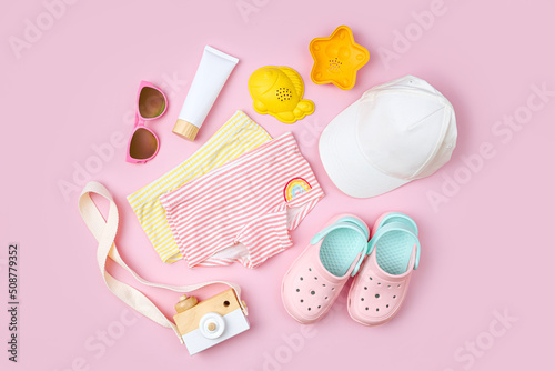 Swimsuit, sunglasses, beach slippers and sunscreen for children. Top view of beach accessories for kids. Summer vacation concept.