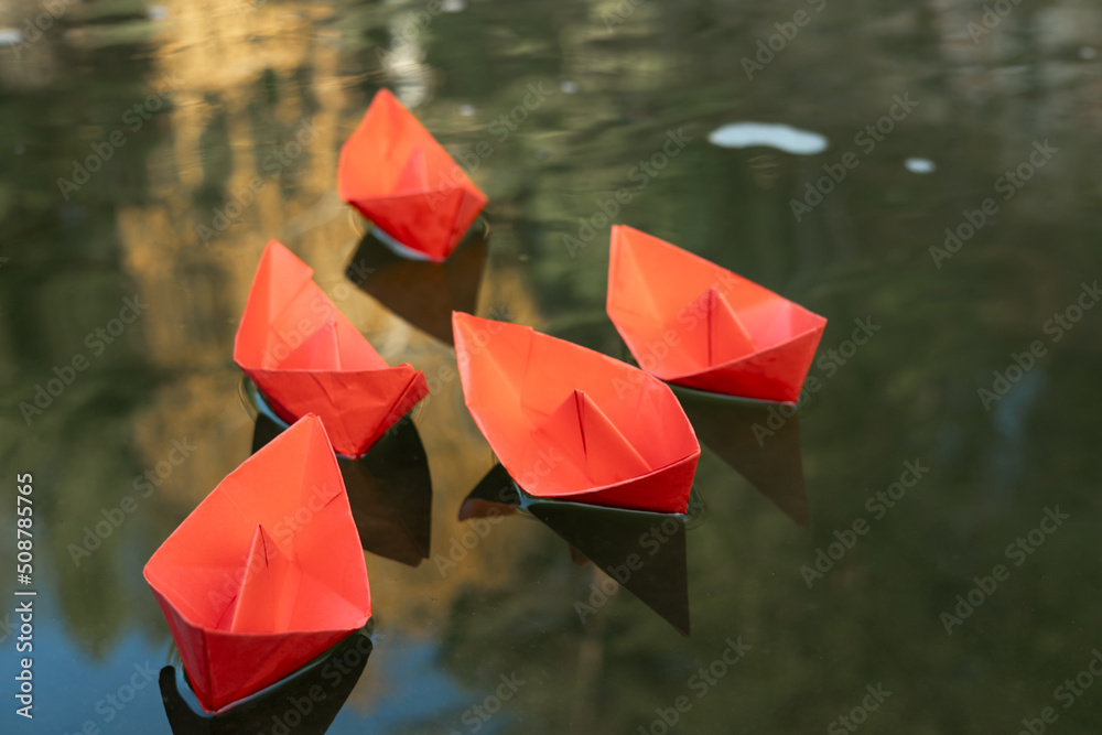 five red paper ships on the water surface