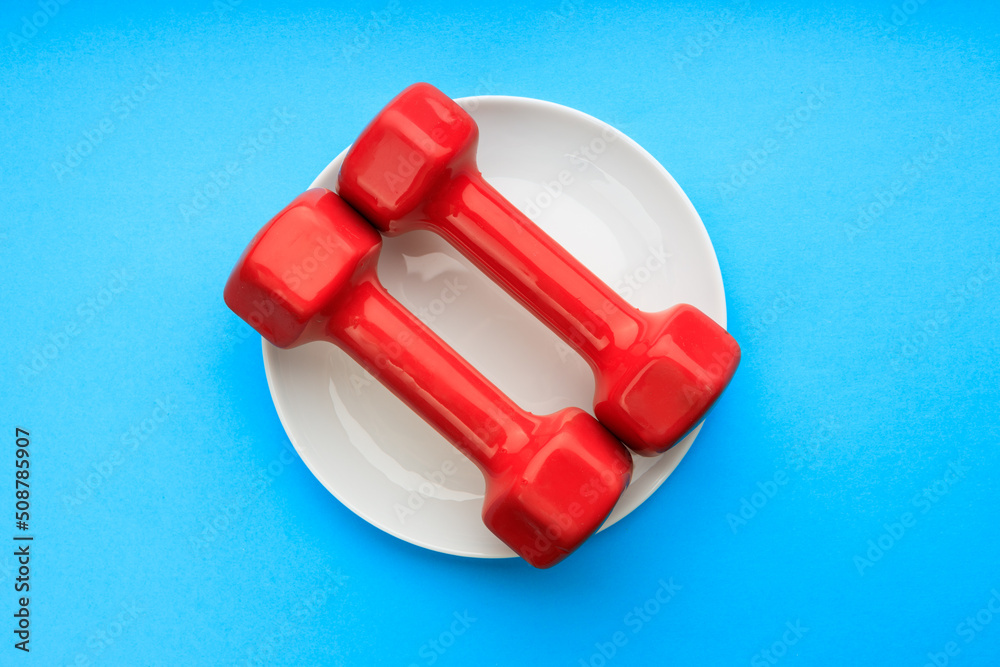 two red dumbbells in a white ceramic plate, the background is blue two red dumbbells in a white ceramic plate, the background is blue