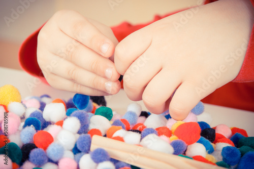 Preschooler playing with small pompoms. Development of kids motor skills, coordination and logical thinking