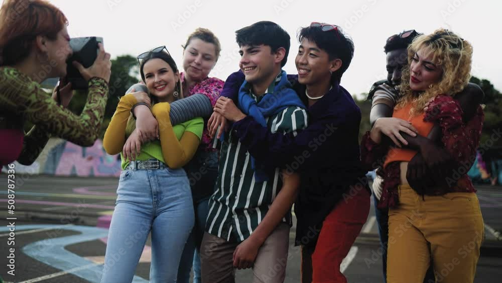 Happy young diverse friends having fun with old vintage video camera outdoor - Youth people millennial generation concept