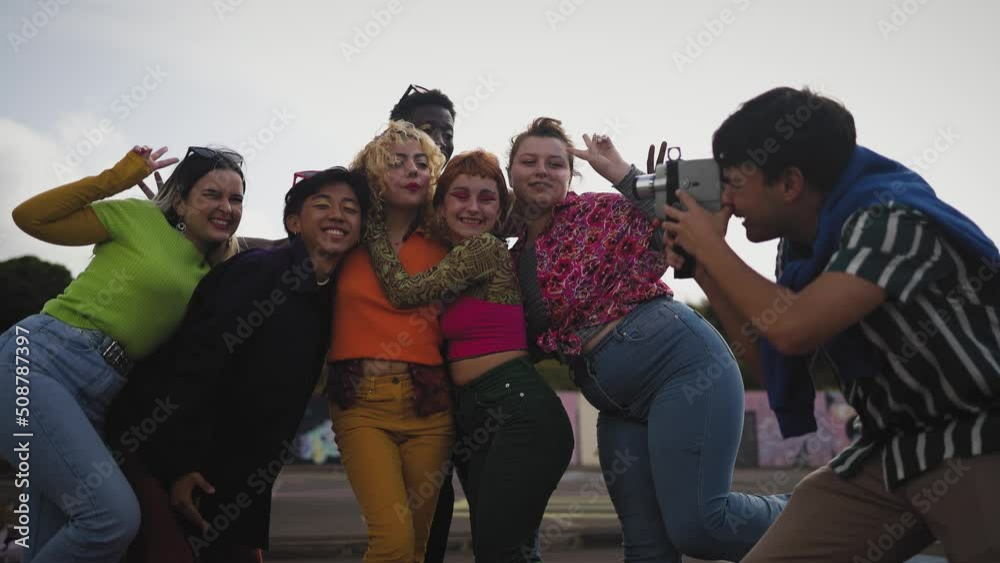 Happy young diverse friends having fun with old vintage video camera outdoor - Youth people millennial generation concept