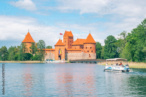 Trakai, Vilnius, Lithuania - June 3 2022: Medieval castle of Trakai, Vilnius, Lithuania, Eastern Europe, surrounded by beautiful lakes and nature in summer with wooden bridge, boats and tourists
