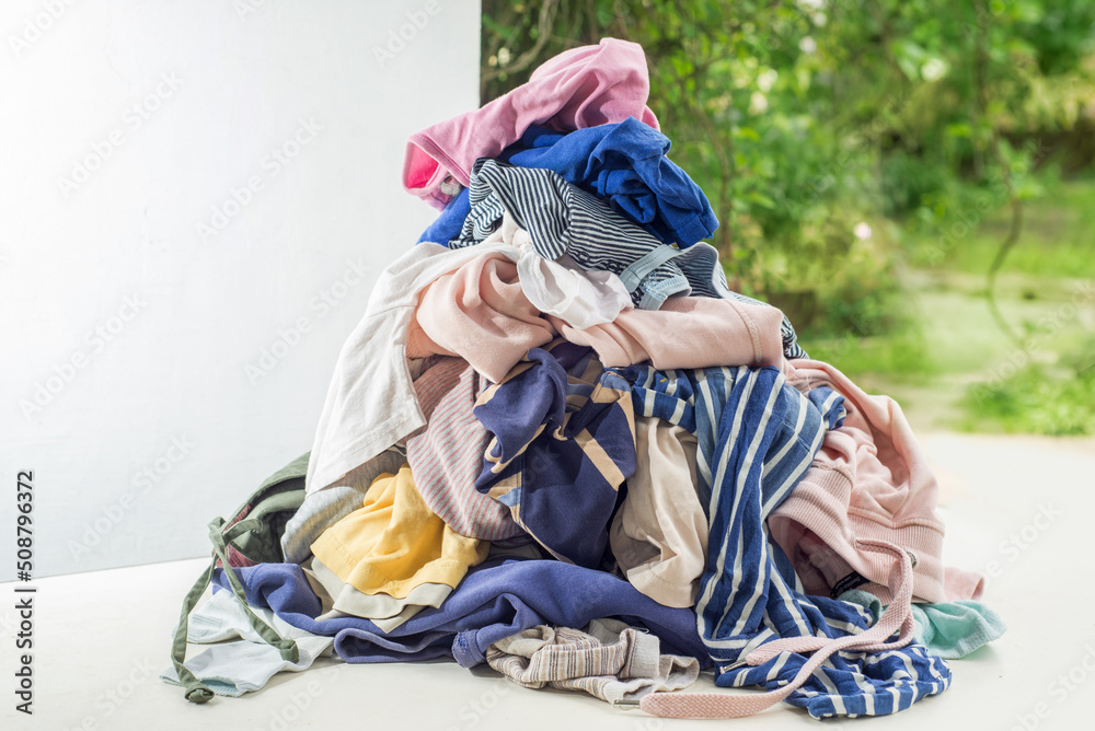 Used clothes in a pile. Sorting and cleaning second-hand. Preparing for washing. Copy space on white background