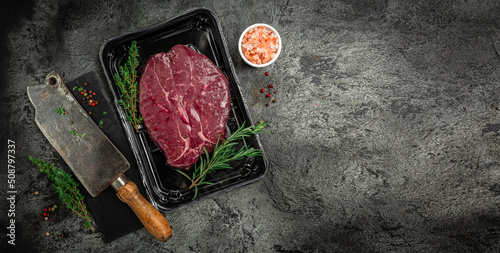 Photo Vacuum pack of 2 raw sirloin beef rump steaks in packed on black background, meat semi finished product