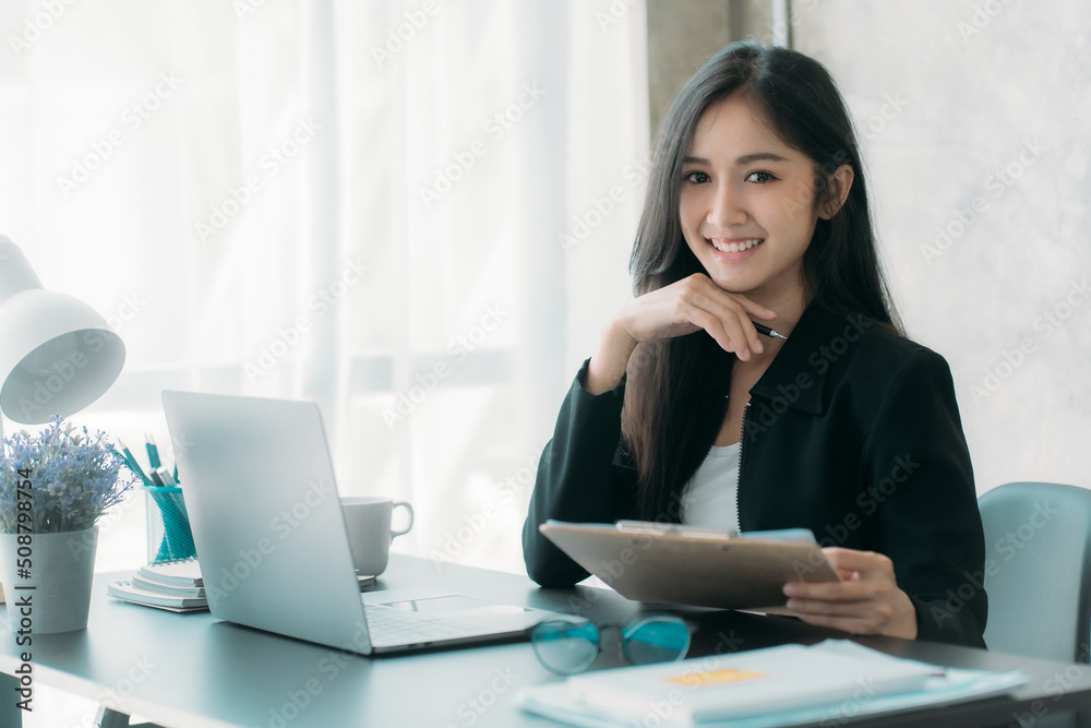 Businesswoman or accountant using the phone to check business information. Accounting Documents and Laptop Computer at Office Business Ideas Businesswoman or accountant using the phone to check business information. Accounting Documents and Laptop Computer at Office Business Ideas
