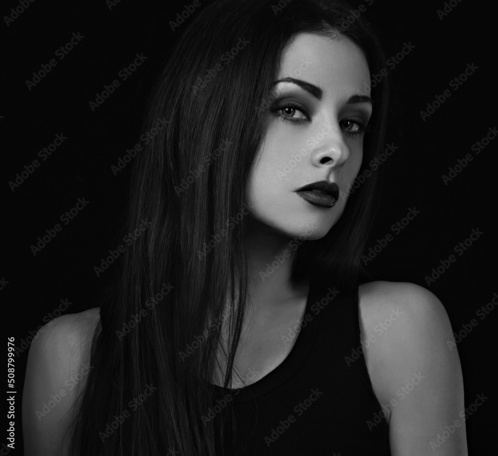 Beautiful bright makeup woman with red lipstick in black top and long brown healthy hair looking on dark black shadow background. Closeup Beautiful bright makeup woman with red lipstick in black top and long brown healthy hair looking on dark black shadow background. Closeup