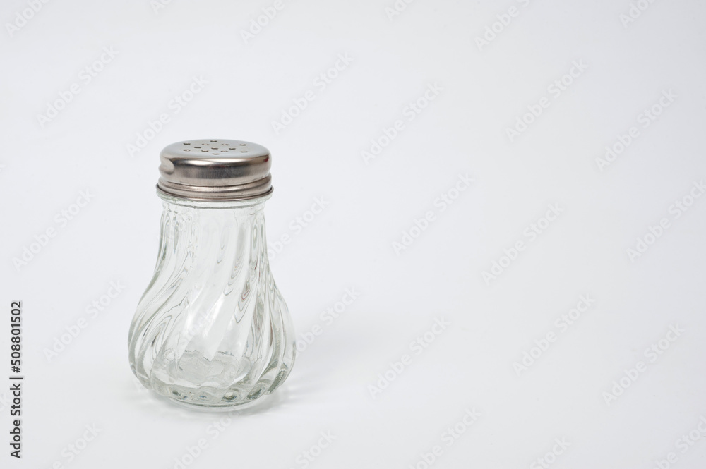 Glass container with a metal screw-on lid with holes for ground pepper. Glass container with a metal screw-on lid with holes for ground pepper.