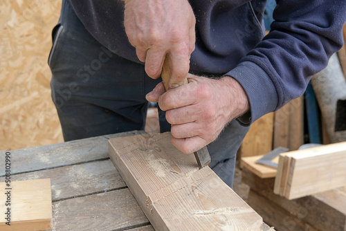 close-up of male hands with a chisel cut wood, carpentry work.