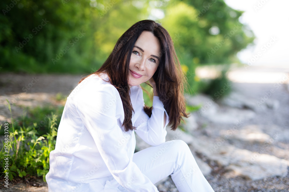 Attraktive und sympathische Frau in weißer Bluse an einem See, Schönheit und Entspannung Attraktive und sympathische Frau in weißer Bluse an einem See, Schönheit und Entspannung
