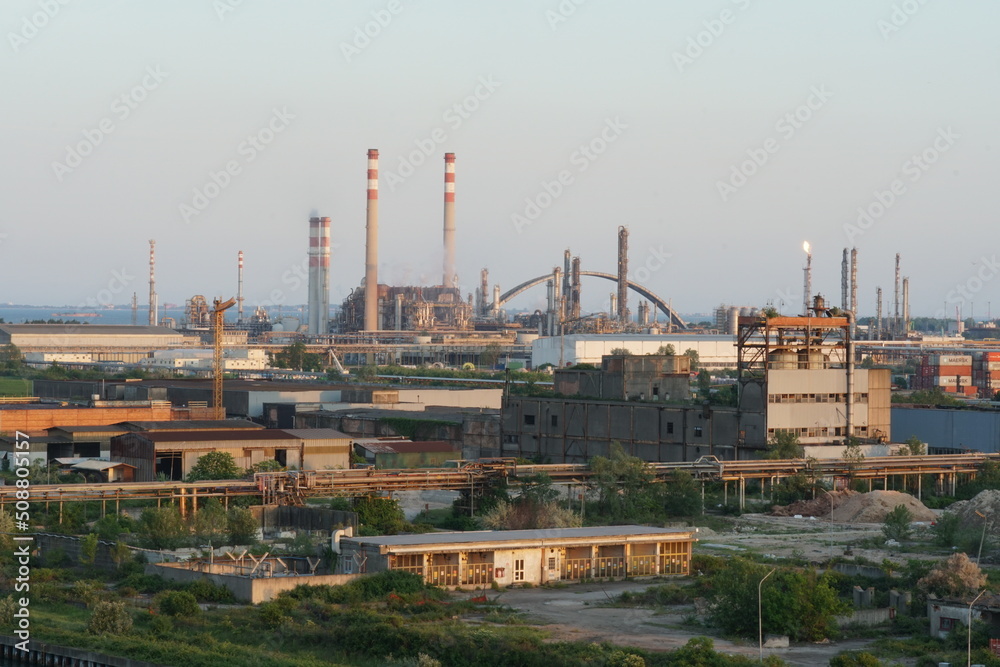 View on Port Marghera industrial part of Venice, Italy from container terminal during sunset. In horizon are factory chimneys and chemical factories. View on Port Marghera industrial part of Venice, Italy from container terminal during sunset. In horizon are factory chimneys and chemical factories.