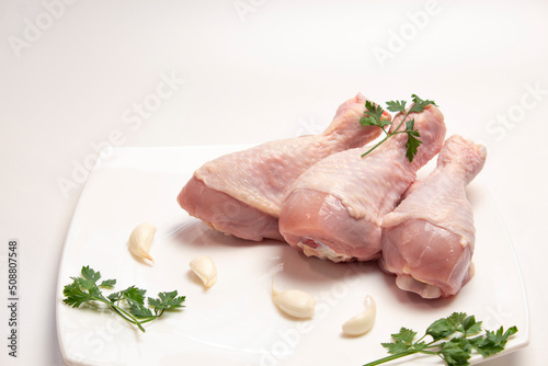 raw chicken legs in a plate on a white background