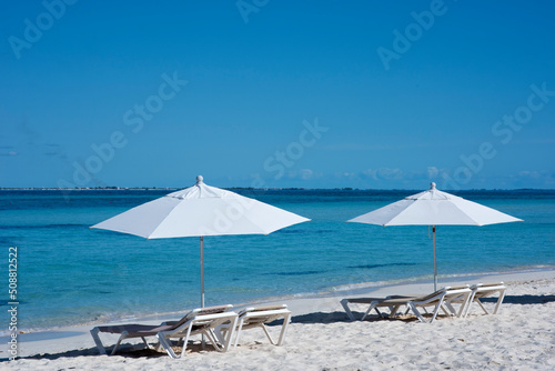 Deserted beach with white umbrellas and sun beds in Isla Mujeres, Mexican Caribbean