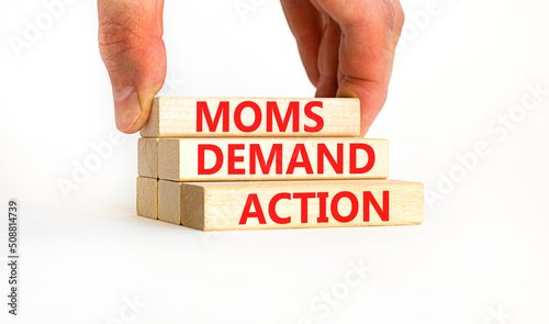 Moms demand action symbol. Concept words Moms demand action on wooden blocks on a beautiful white table white background. Businessman hand. Business, finacial and Moms demand action concept. photo