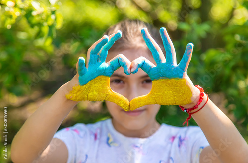 A child with the flag of Ukraine painted on his hands. Selective focus.