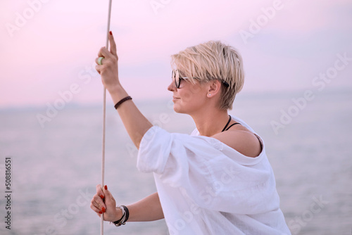 Beautiful blonde happy woman enjoying sunset on the yacht in the sea. Travel, adventure, relaxation concept 